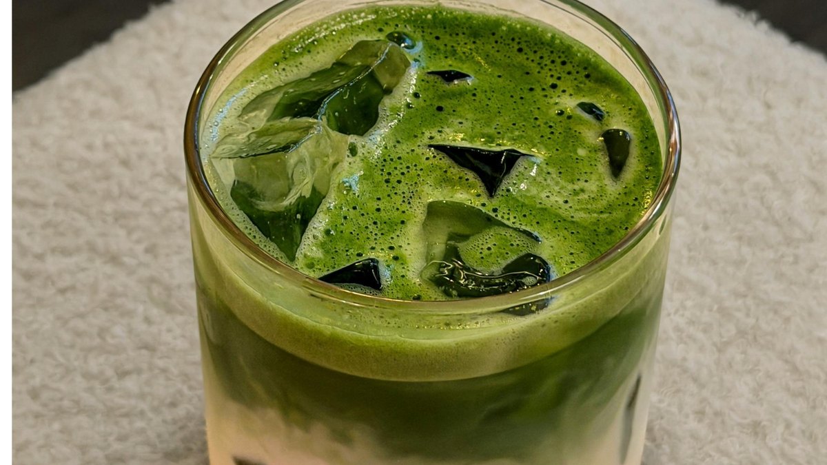 An iced matcha latte in a tall glass on a cafe table