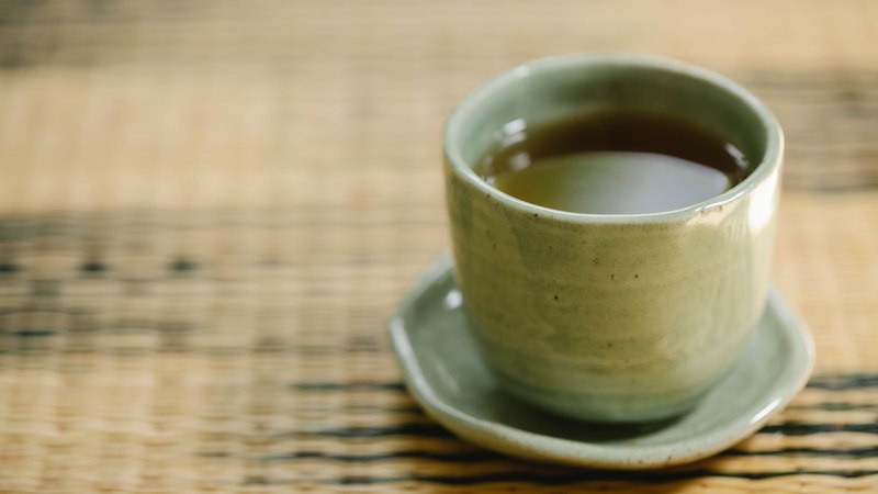 A cup of amber roasted hojicha in a celadon cup