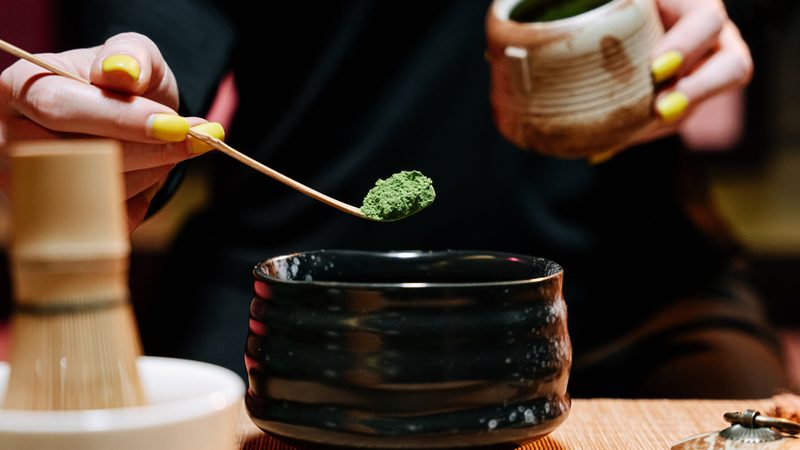 A bowl of whisked matcha beside brewed green tea