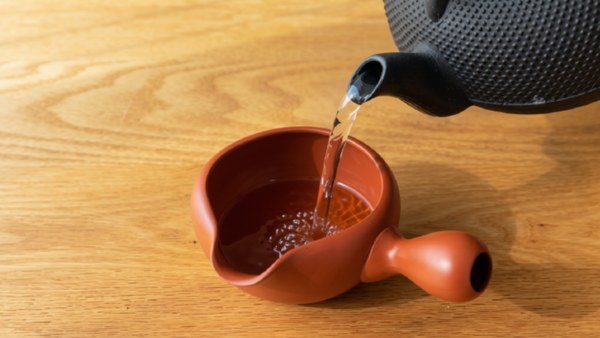 An iron kettle pouring into a clay yuzamashi