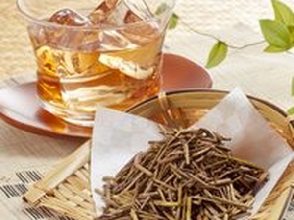 Roasted hojicha leaves beside a glass of iced tea