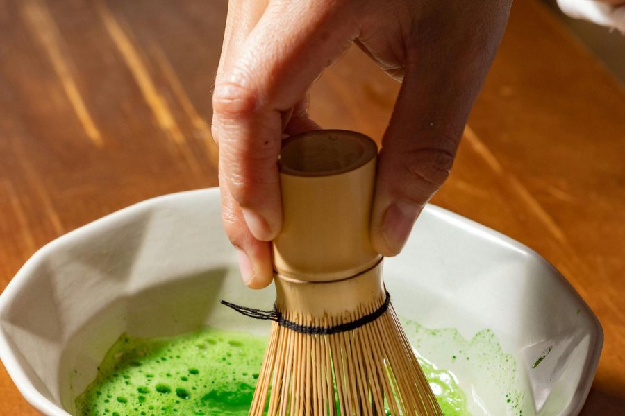 A bowl of sifted matcha powder with hot water being added