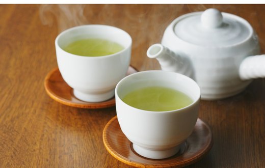 Two cups of green tea with a white teapot
