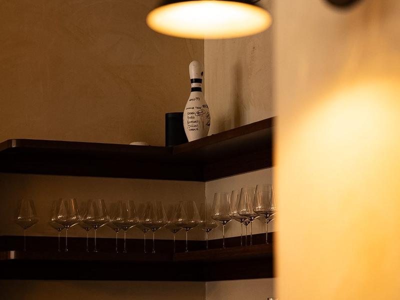 A shelf of wine glasses under a warm lamp inside the host restaurant